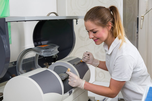 Dental assistant using CEREC technology to produce dental crowns at East Village Dental Centre in Chicago.