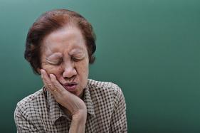 Older woman with a toothache holding her jaw in pain