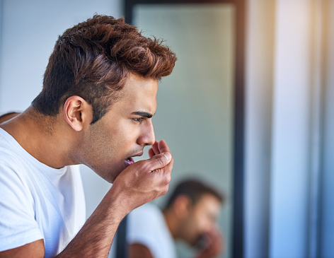 Man cusping his hand in front of his mouth to check his breath.