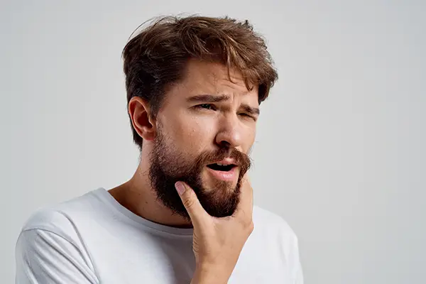 A man holding his jaw due to the pain from of TMD.