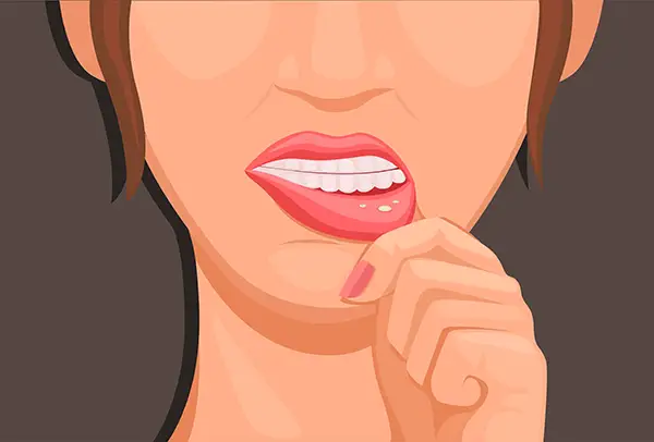 A woman inspects a visible cold sore or canker sore.